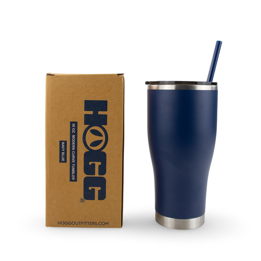 Navy blue tumbler with silver base and straw next to a cardboard box with 'HOGG' branding.